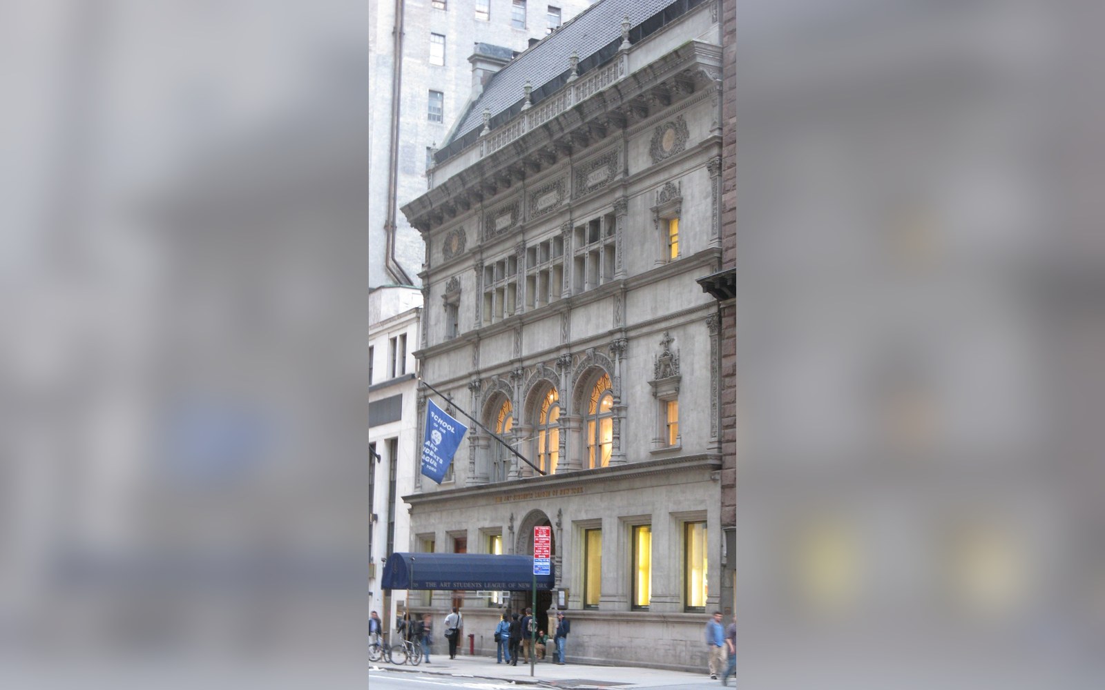 Ornate stone facade of the Art Students League building with arched windows and a blue banner