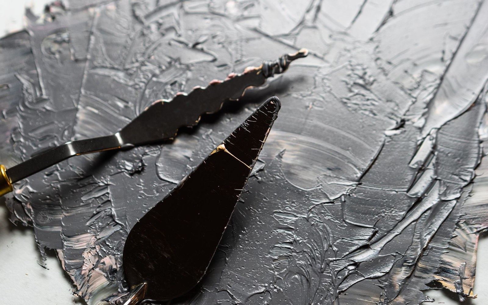 A palette knife loaded with lead white oil paint, impasto texture clearly visible, close-up
